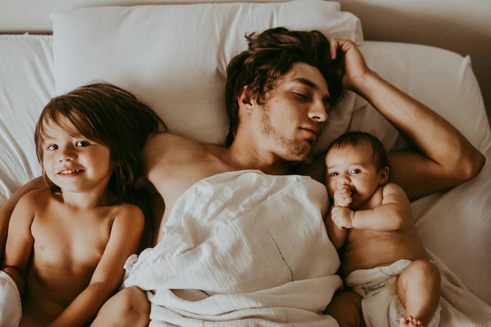 dad lying in bed with 2 small children