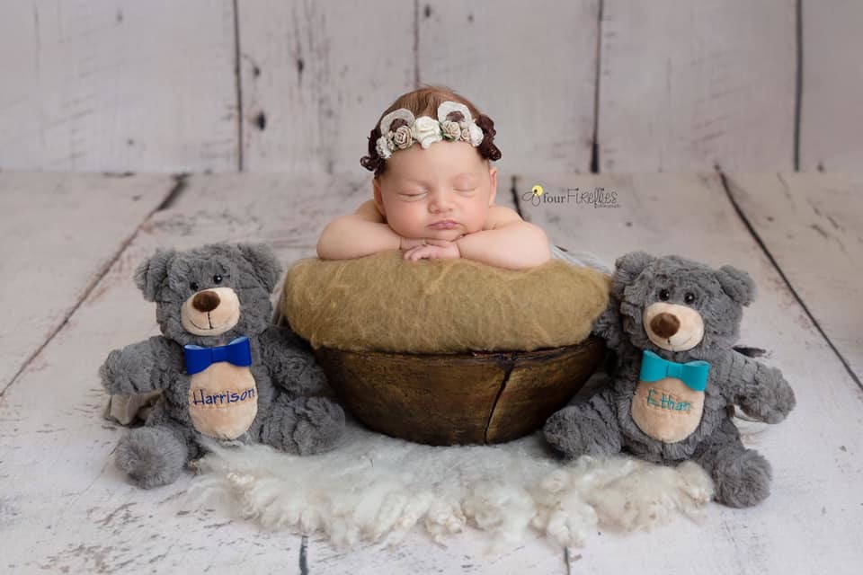 newborn posed in bowl with 2 teddy bears beside her