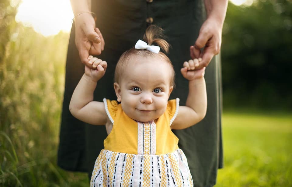 baby girl being held up by parent's hands