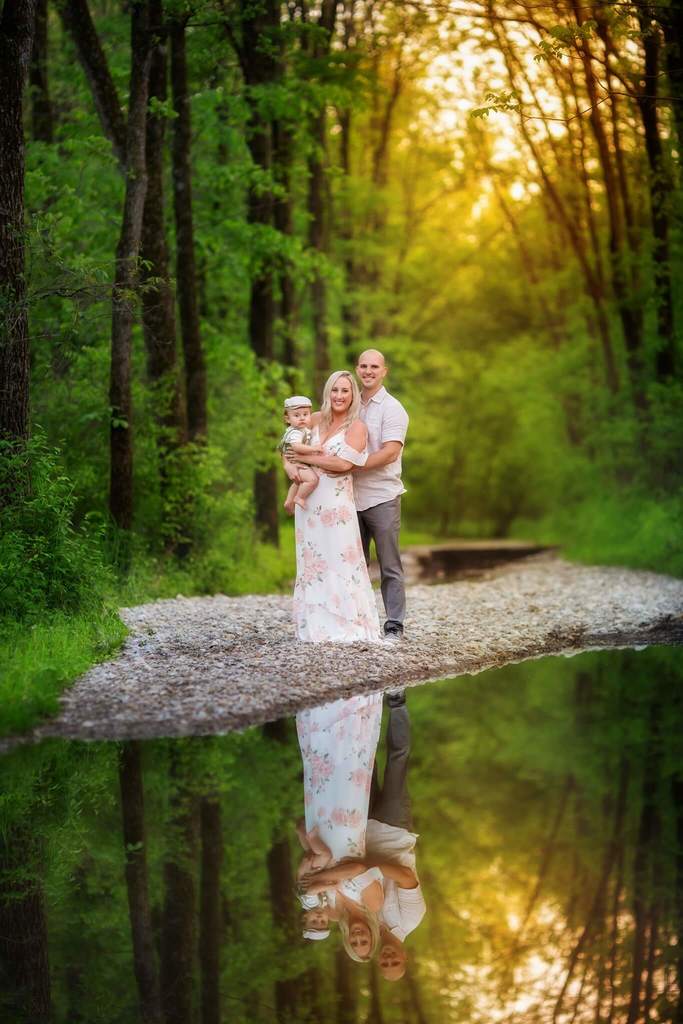 couple posing with baby in creek