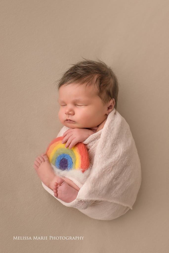 newborn wrapped baby holding felt rainbow