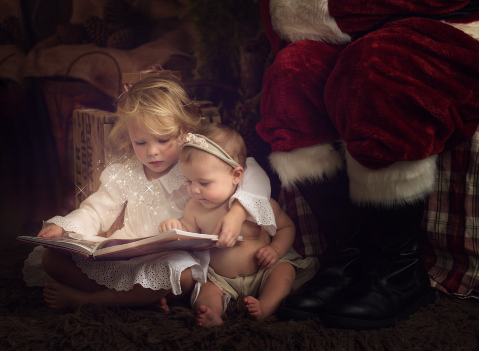 2 kids reading with Santa looking on