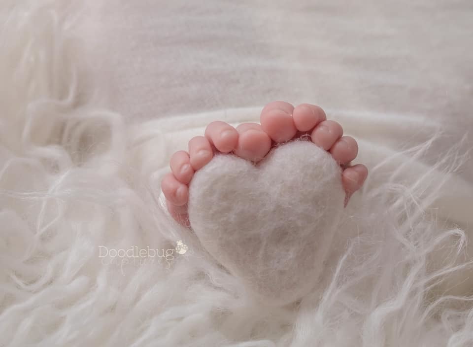 newborn feet wrapped around felted heart