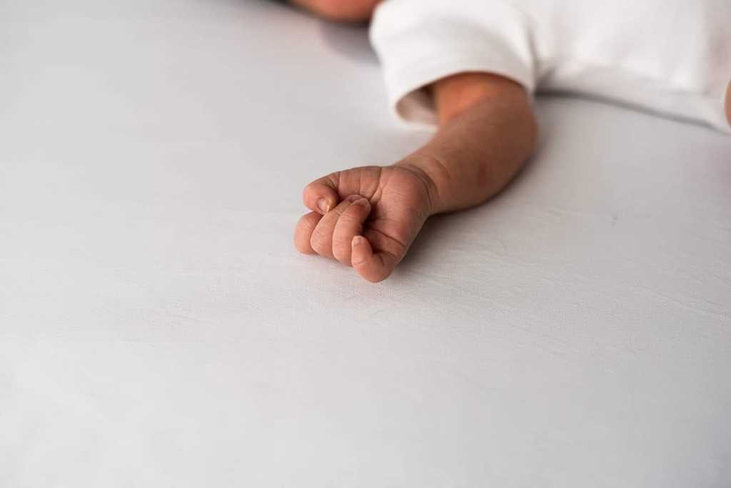 baby fist on white blanket