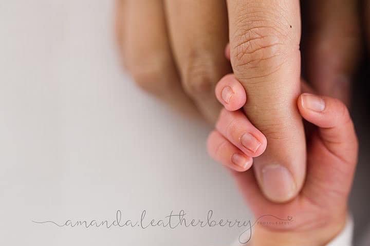 newborn hand clutching adult finger
