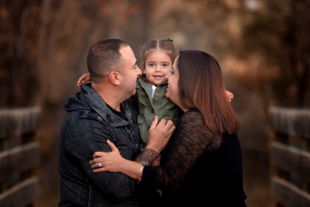 parents kissing child in family photo session