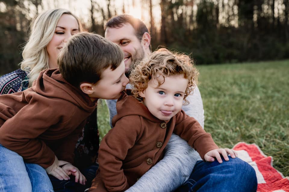 brother giving sibling kiss during family session