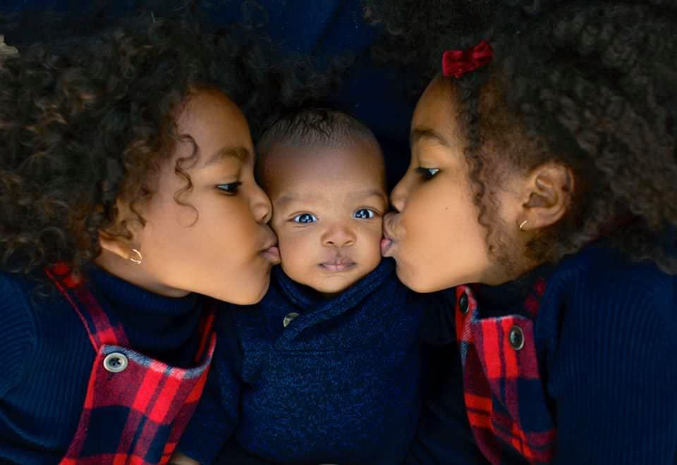 baby being kissed by two siblings