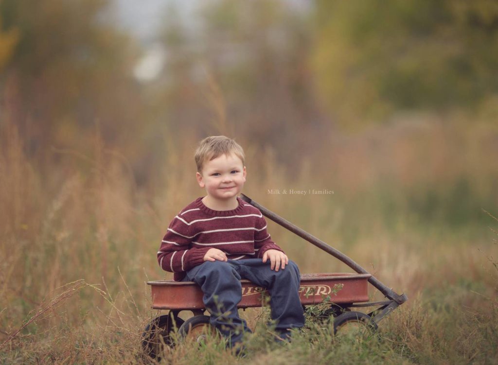 child sitting in wagon in field