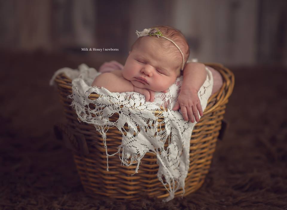 prop posing newborn in basket with head on chin