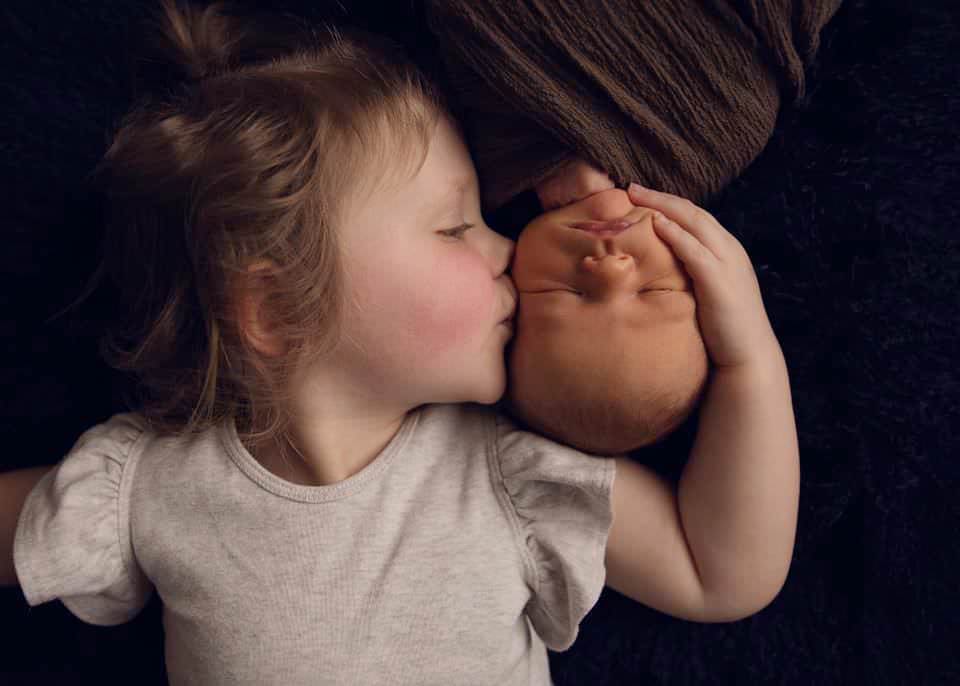 girl kissing newborn sibling
