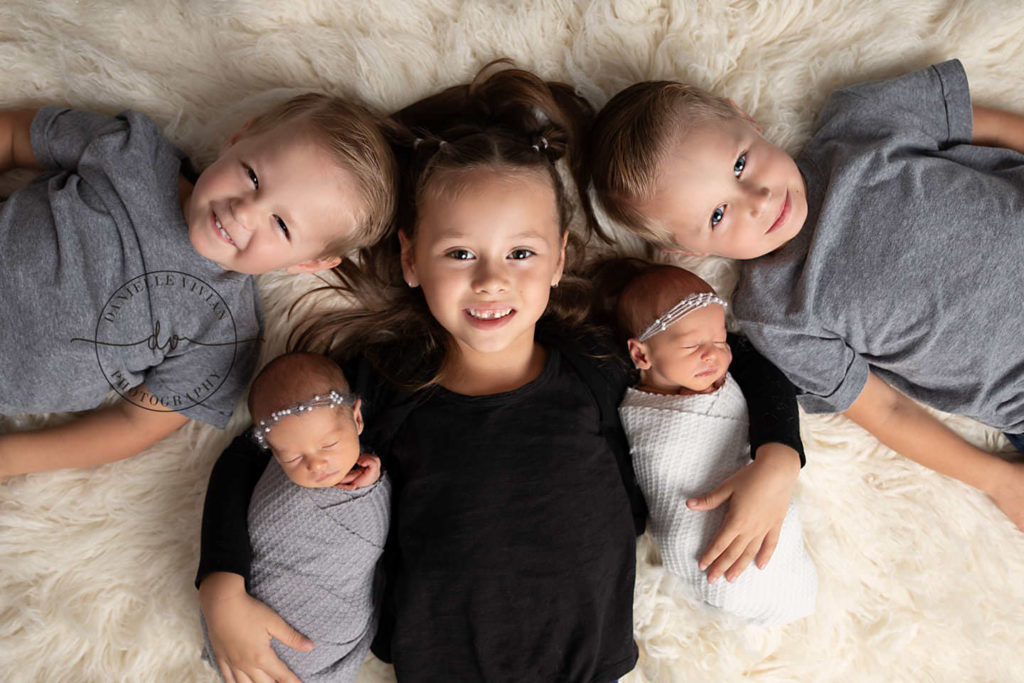 sibling poses with newborn and multiple siblings