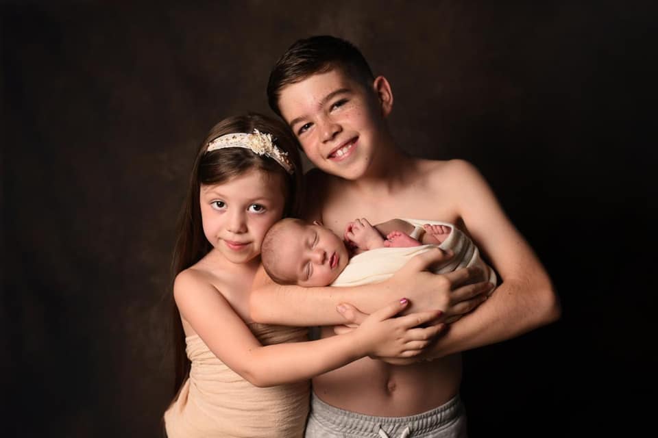 boy and girl holding newborn baby